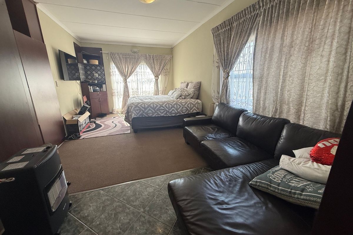 A multi-functional bedroom space featuring a combination of tiled and carpeted flooring, built-in cabinetry, and dual window treatments.