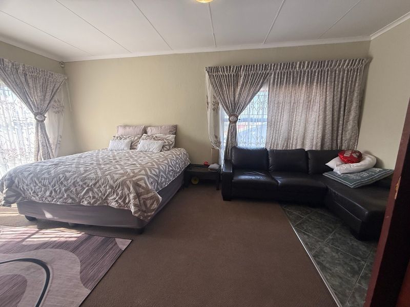 Spacious bedroom featuring a combination of carpeted and tiled flooring, with security bars on the windows.
