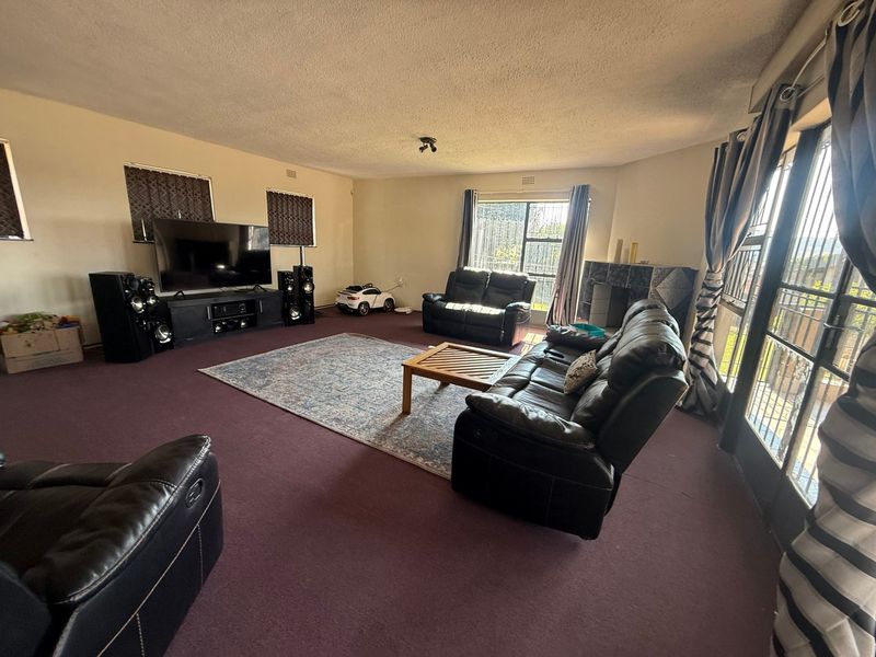 Spacious living room featuring a fireplace, large sliding glass doors with security gates, and wall-to-wall carpeting.