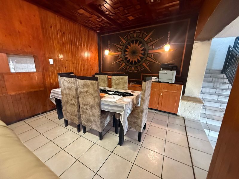 Dining area featuring wood-paneled walls, tiled flooring, and built-in cabinetry, adjacent to an internal staircase.