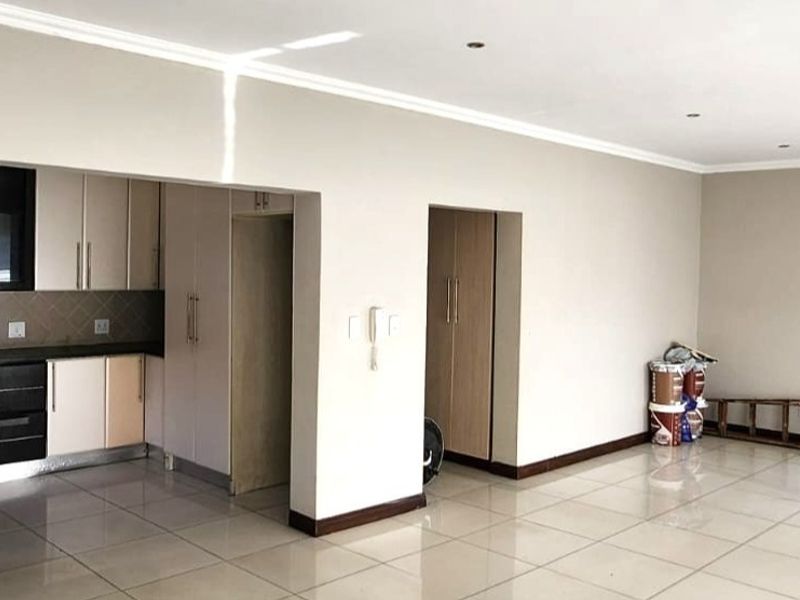 Spacious open-plan living area featuring tiled flooring, recessed lighting, and a modern kitchen with built-in cabinetry, hob, and extractor fan.
