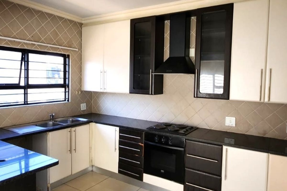 A functional kitchen featuring two-tone cabinetry, granite countertops, a built-in oven with gas hob, and a tiled backsplash.