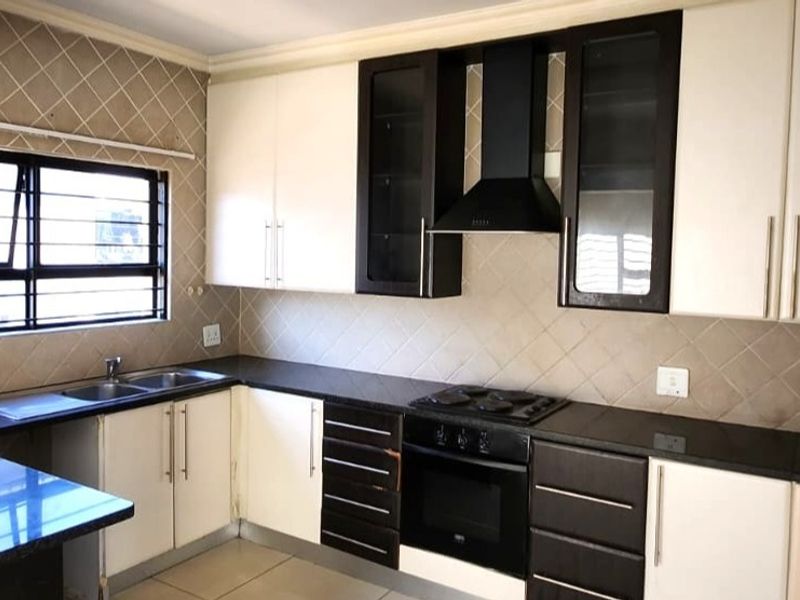 A functional kitchen featuring two-tone cabinetry, granite countertops, a built-in oven with gas hob, and a tiled backsplash.