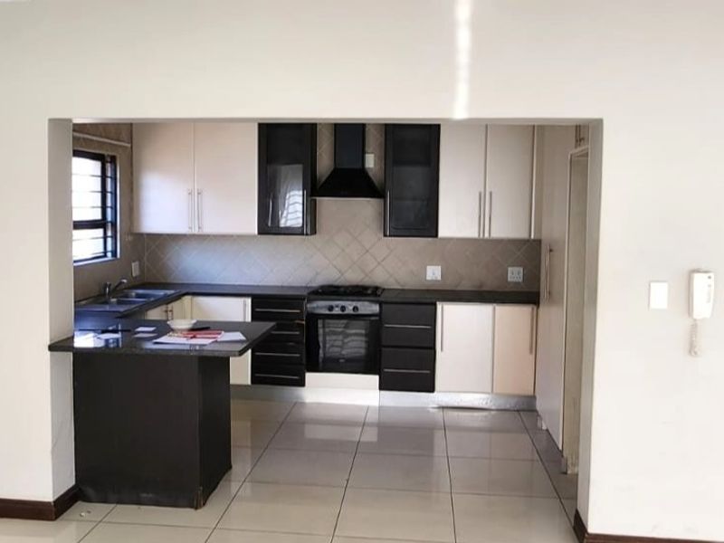 A functional kitchen featuring built-in cabinetry, granite countertops, a built-in oven with extractor fan, and tiled flooring, presented in a clean, open-plan layout.