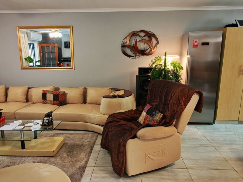 Open-plan living area featuring tiled flooring, integrated kitchen cabinetry, and a ceiling fan, creating a functional and connected living and kitchen space.
