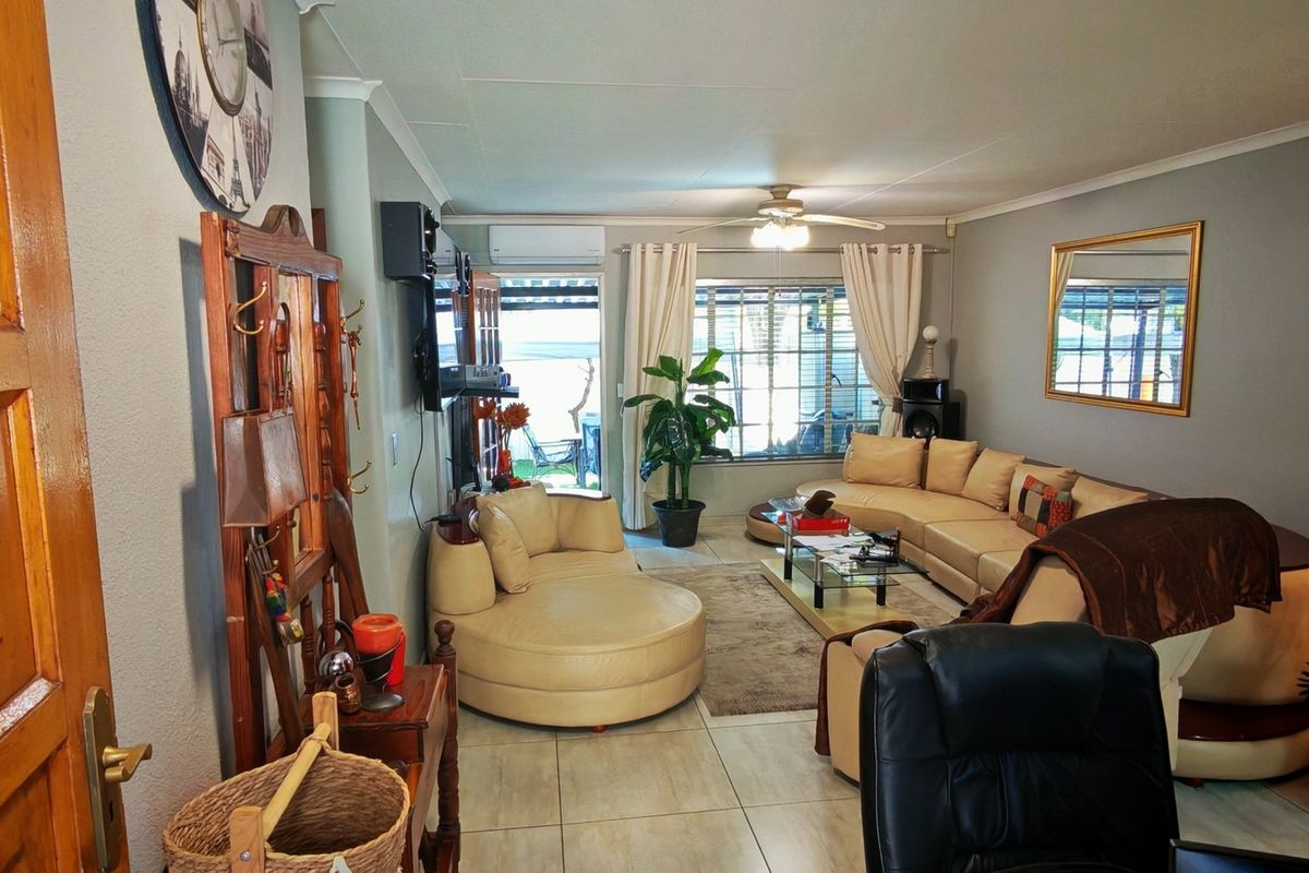 A comfortable living room featuring tiled flooring, a ceiling fan, and an air conditioning unit, with direct access to an outdoor patio area.