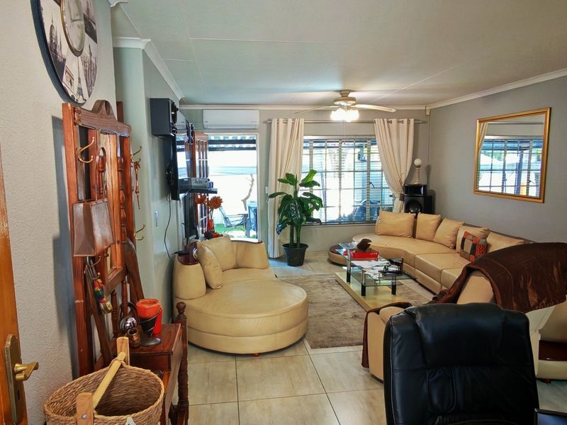 A comfortable living room featuring tiled flooring, a ceiling fan, and an air conditioning unit, with direct access to an outdoor patio area.