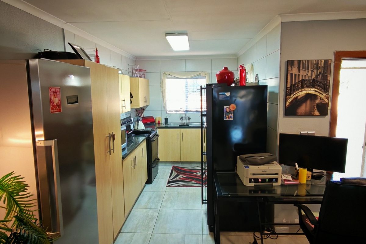 A functional kitchen featuring light wood-finish cabinetry, tiled flooring, and a tiled backsplash, providing a practical workspace with integrated appliances.