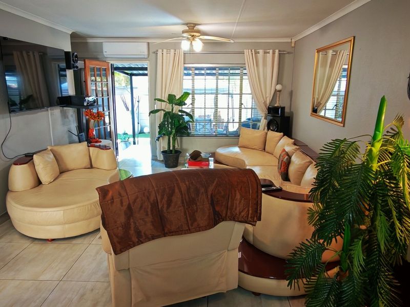 A comfortable living room featuring tiled flooring, a ceiling fan, and a split-system air conditioner, with direct access to an outdoor patio area.