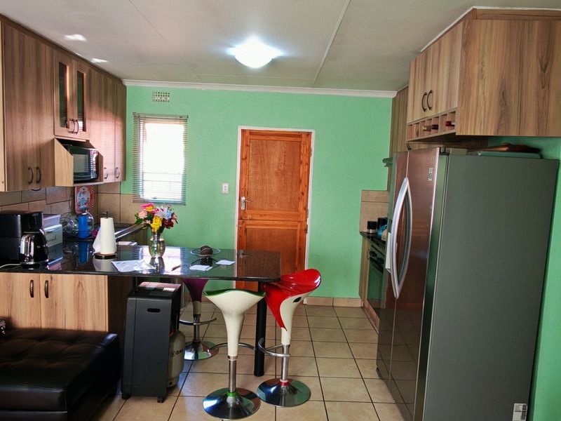 A functional kitchen featuring wood-finish cabinetry, granite countertops, tiled flooring, and integrated appliances, offering a practical layout for daily cooking and dining.