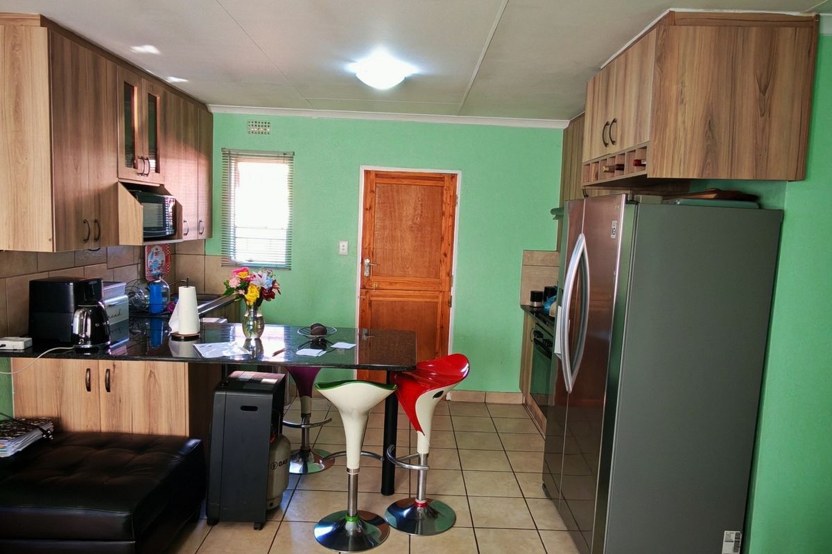 A functional kitchen featuring wood-finish cabinetry, granite countertops, tiled flooring, and integrated appliances, offering a practical layout for daily cooking and dining.