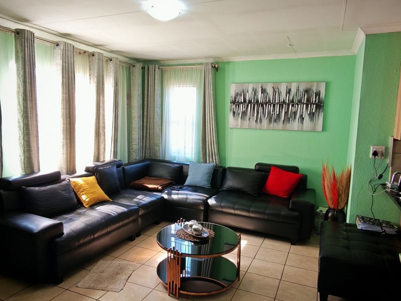 Open-plan living area featuring tiled flooring and a compact kitchen with built-in cabinetry and granite countertops.