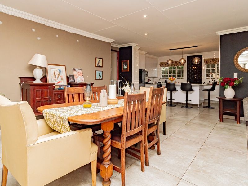 Spacious open-plan dining and kitchen area featuring tiled flooring, modern pendant lighting, and a central kitchen island with breakfast bar seating.