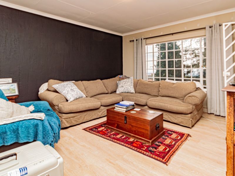 A comfortable living room featuring light-toned laminate flooring, a large grid-pattern window, and a dark accent wall.