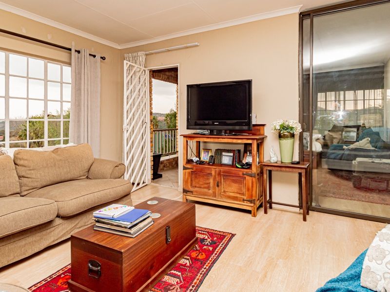 A comfortable living room featuring laminate flooring, large windows for natural light, and direct access to an outdoor balcony area.