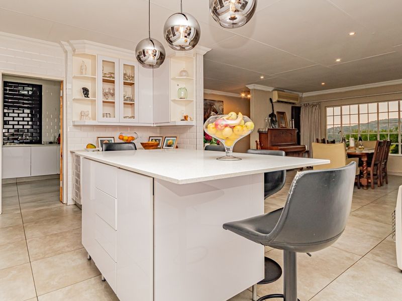 Spacious open-plan kitchen and living area featuring a central island with quartz countertops, modern cabinetry, and tiled flooring throughout.
