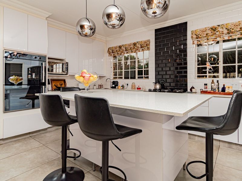 Modern kitchen featuring a central island with stone countertops, built-in oven, microwave, gas hob, and stylish subway tile backsplash with ample cabinetry.