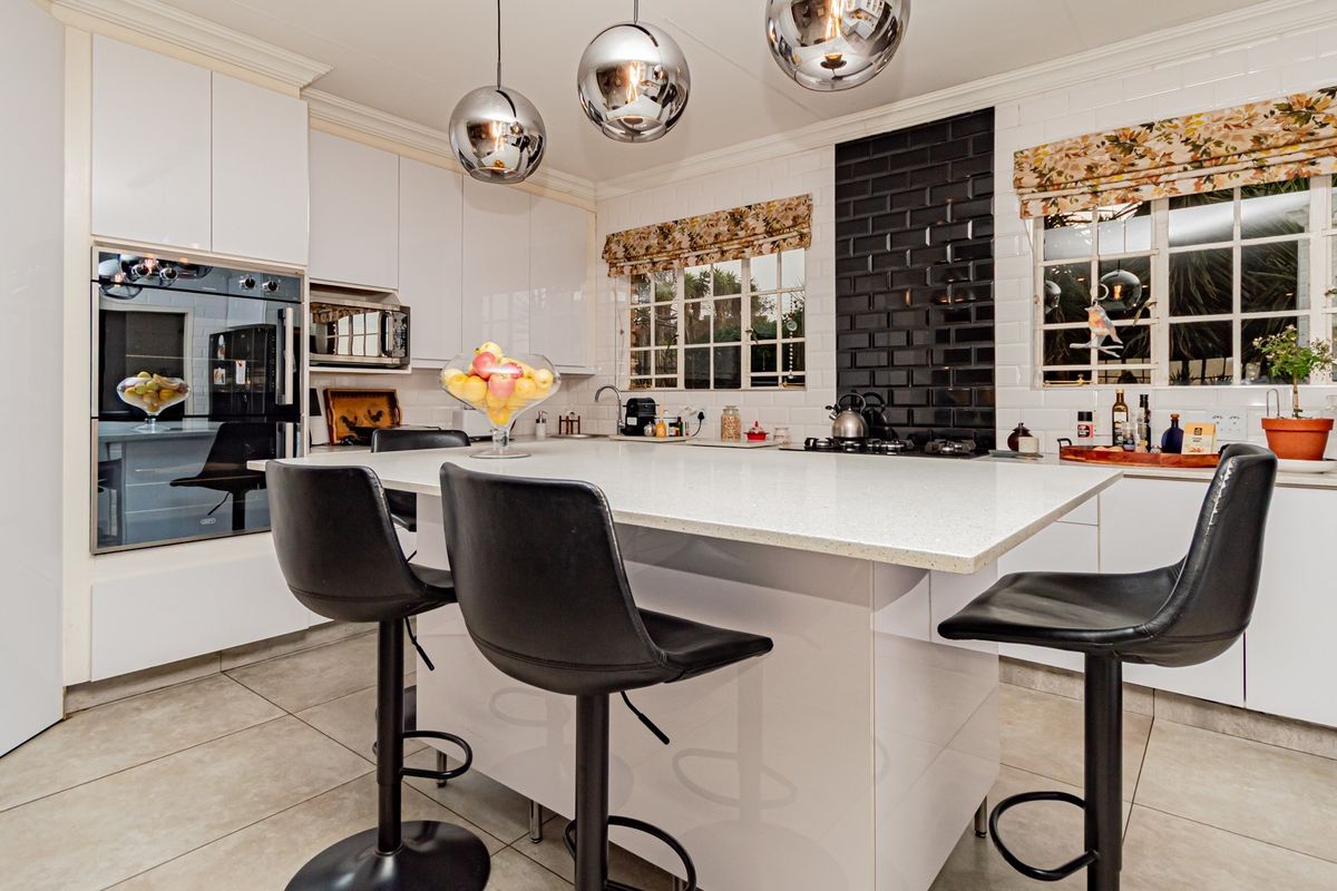 Modern kitchen featuring a central island with stone countertops, built-in oven, microwave, gas hob, and stylish subway tile backsplash with ample cabinetry.
