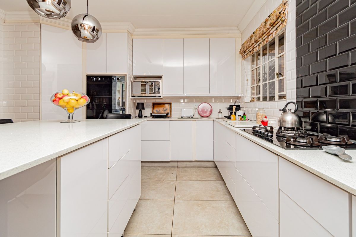 Modern kitchen featuring white gloss cabinetry, quartz countertops, a gas hob, built-in oven, and stylish subway tile backsplash.