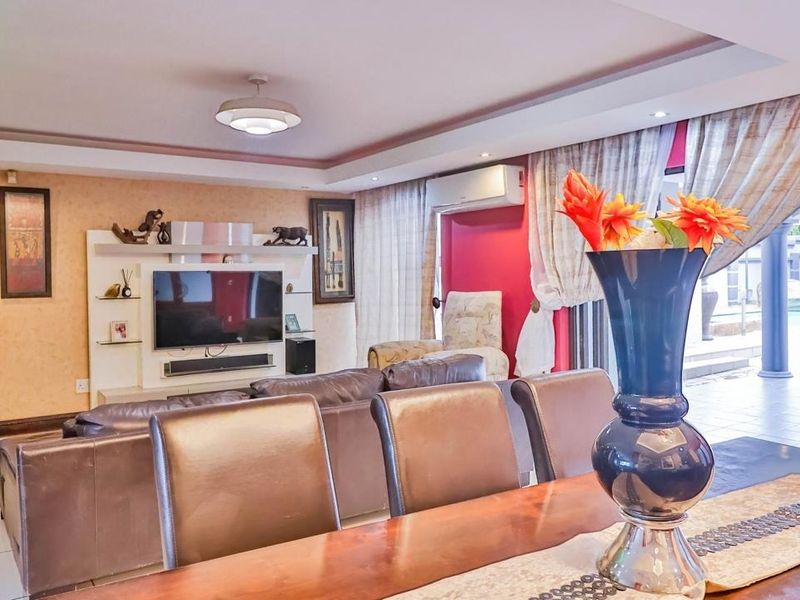 Spacious open-plan living and dining area featuring tiled floors, recessed ceiling lighting, a built-in media unit, and direct access to the outdoor patio.