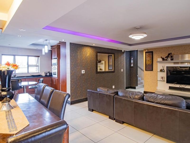 Spacious open-plan living and dining area featuring modern recessed lighting, tiled floors, and a well-integrated kitchen with built-in cabinetry.
