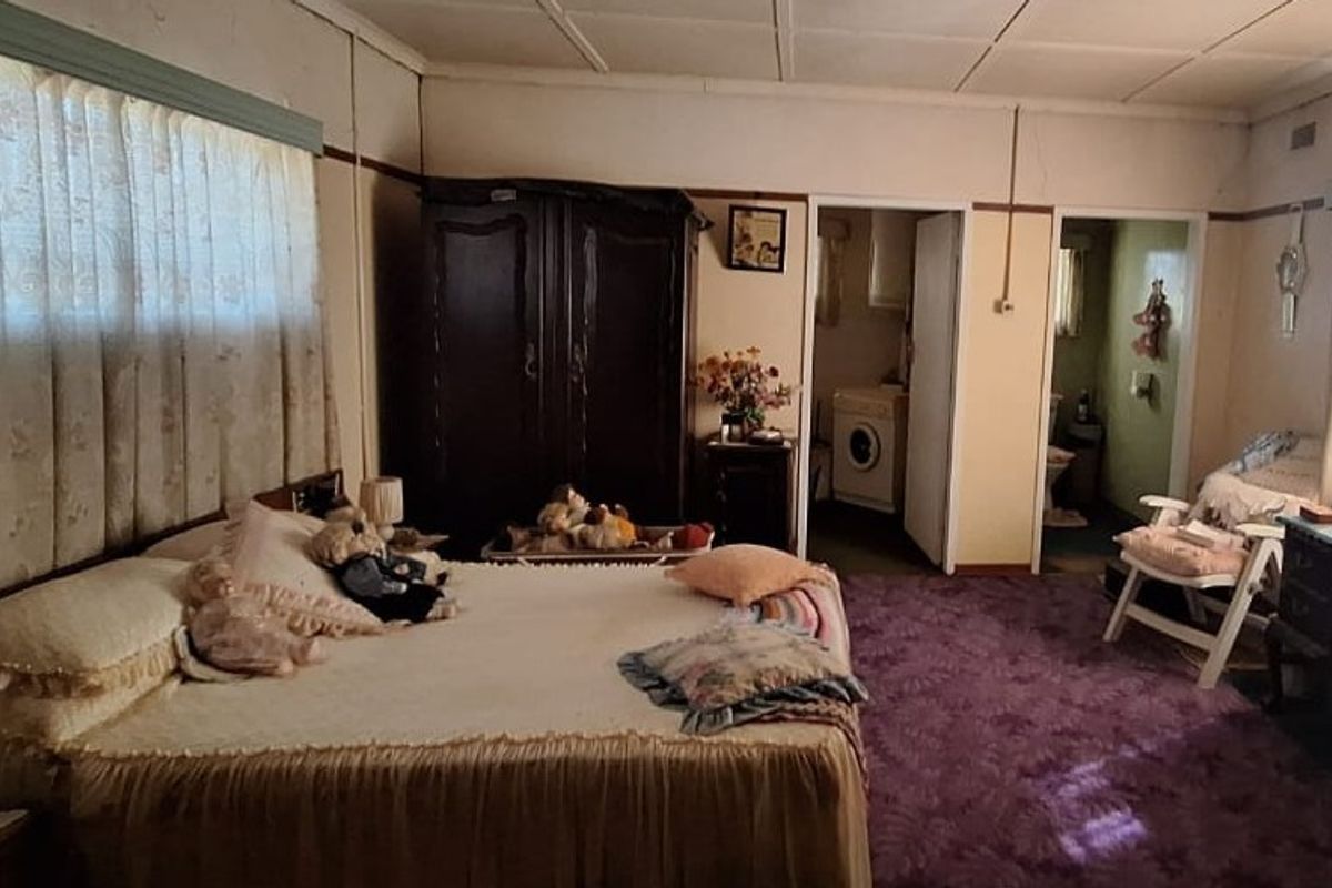 Spacious bedroom featuring built-in cupboards, carpeted flooring, and direct access to an adjoining utility area and bathroom.