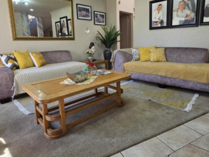 A comfortable living room featuring a mix of tiled and carpeted flooring, complemented by a large wall-mounted mirror.
