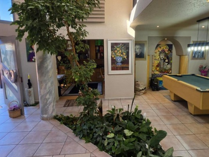 Spacious entrance hall featuring tiled flooring, a central indoor planter bed, and an open-plan layout leading into a recreational area.