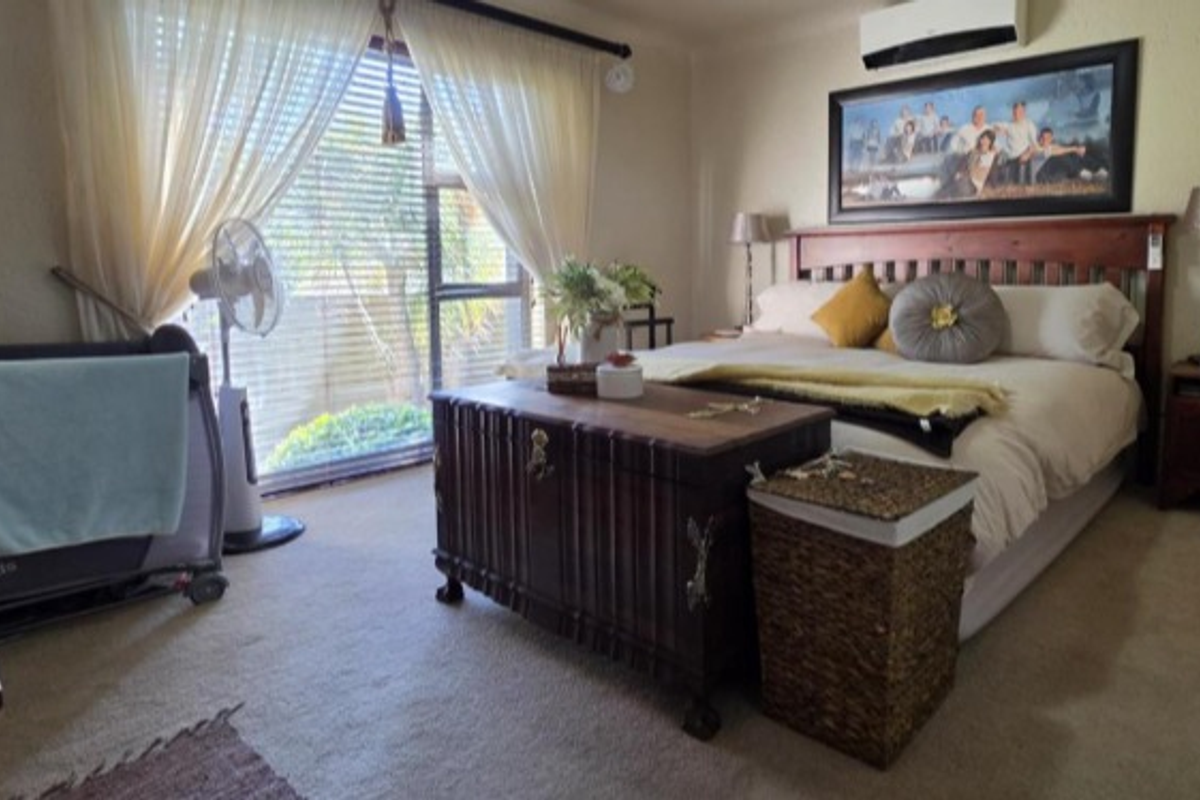 A carpeted bedroom featuring a split-system air conditioner and a sliding glass door providing natural light.