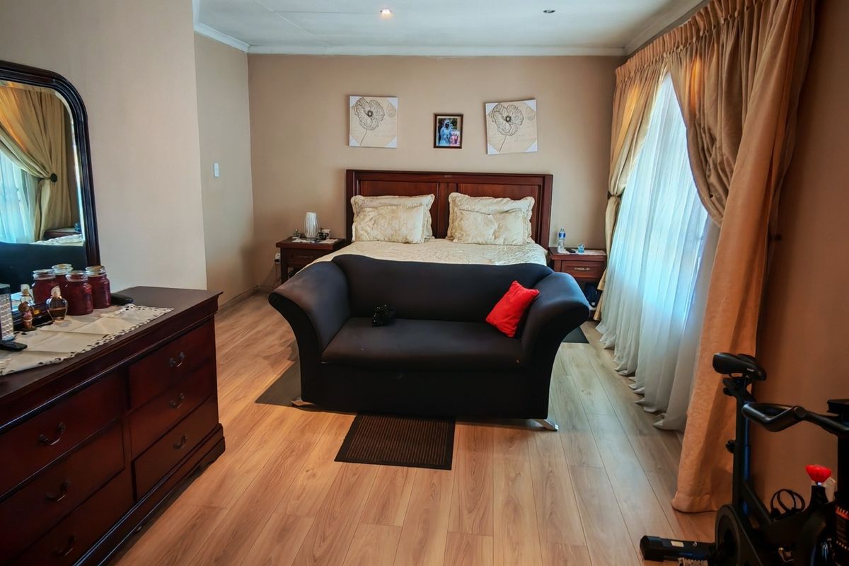 A spacious bedroom featuring laminate flooring and recessed ceiling lighting, offering a comfortable layout with ample natural light from the window.