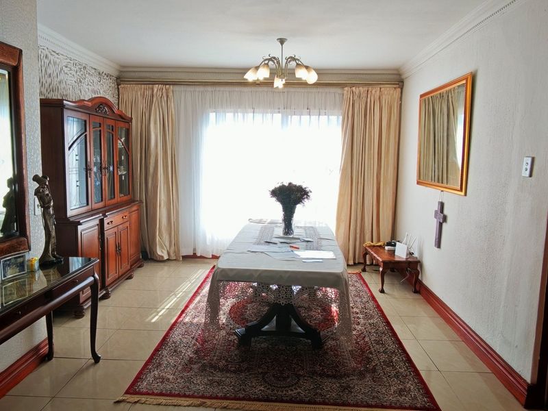 A formal dining room featuring tiled flooring, coved ceilings, and a central light fixture, providing a classic space for family meals.