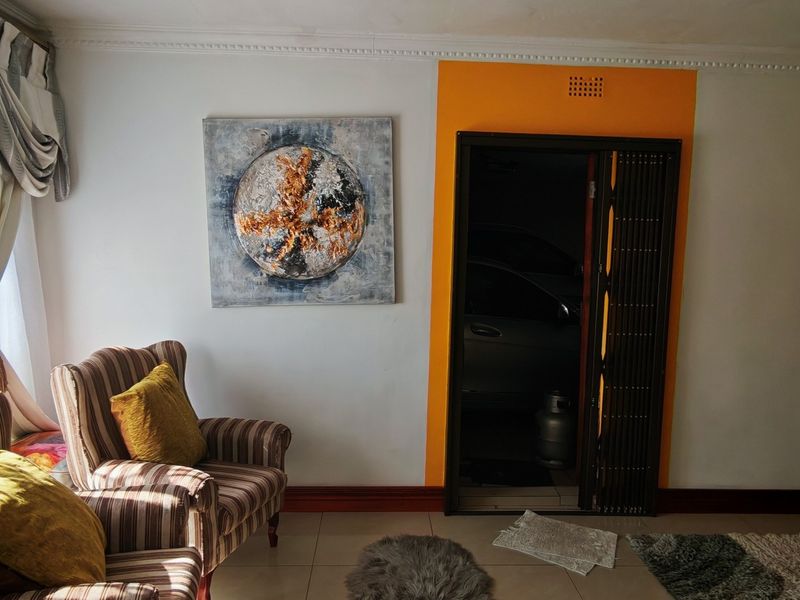 A living room area featuring tiled flooring, decorative ceiling cornicing, and a folding door leading to an adjacent space.