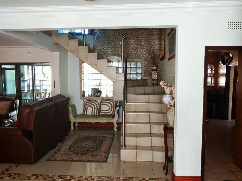 Spacious living area featuring a tiled staircase with stainless steel balustrade, coved ceiling cornices, and direct access to an outdoor patio area.