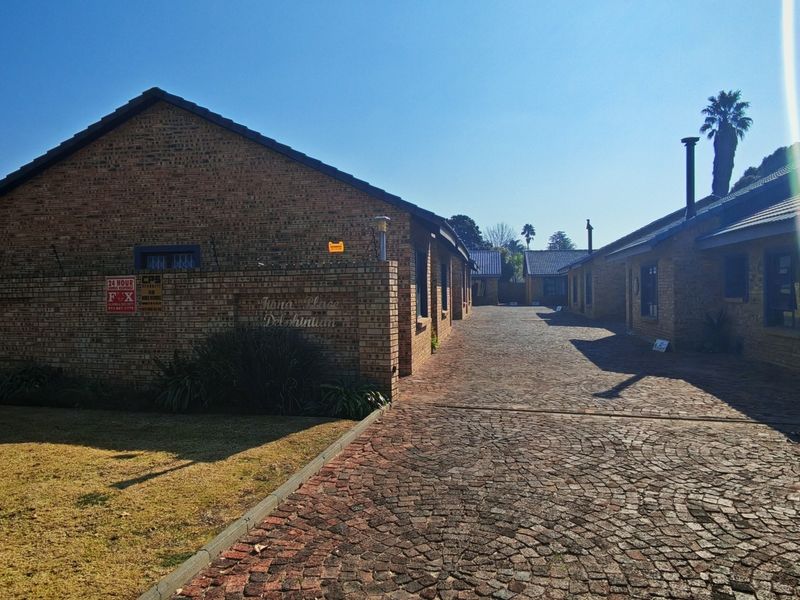 A view of the complex entrance featuring face-brick buildings, a cobblestone driveway, and established perimeter security walls.