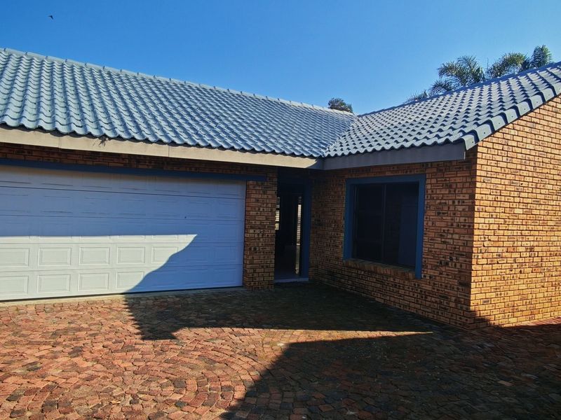 Front elevation of a face brick cluster home featuring a tiled roof, paved driveway, and a double garage.
