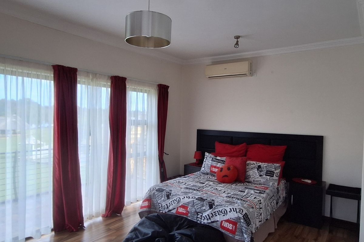 Spacious bedroom featuring laminate flooring, air conditioning, and large sliding glass doors that provide natural light and access to an outdoor area.
