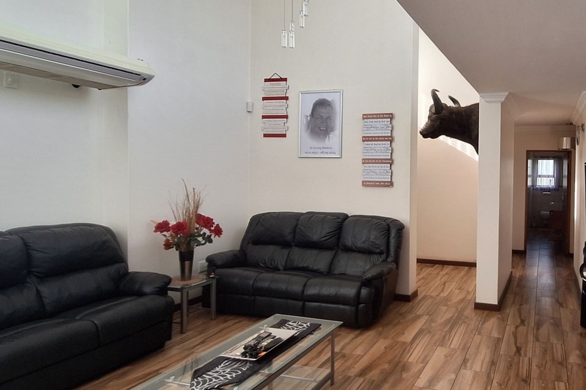 Spacious living room featuring high ceilings, laminate flooring, and a wall-mounted air conditioning unit, providing a comfortable and open living environment.