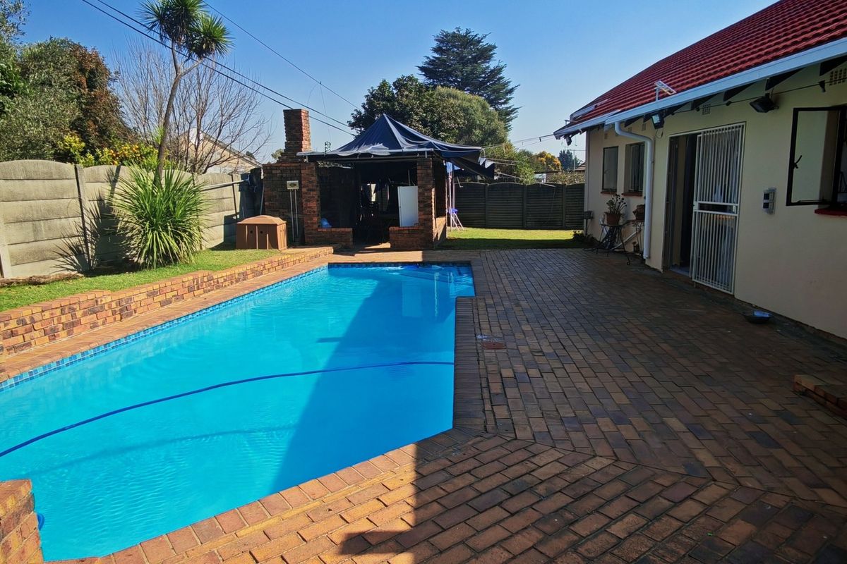 Outdoor pool area featuring a swimming pool, brick paved patio, and a built-in braai structure, set within a private garden with boundary walls.