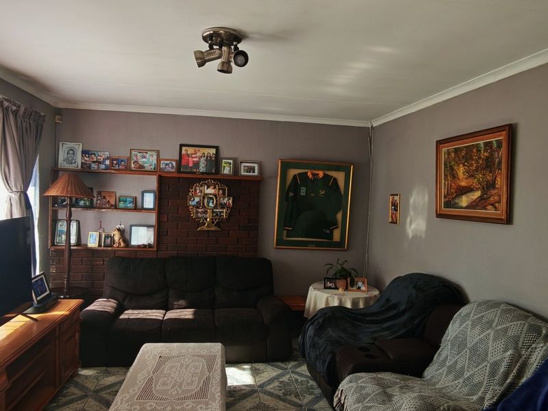 A living room featuring a brick fireplace with built-in shelving, tiled flooring, and neutral wall finishes.