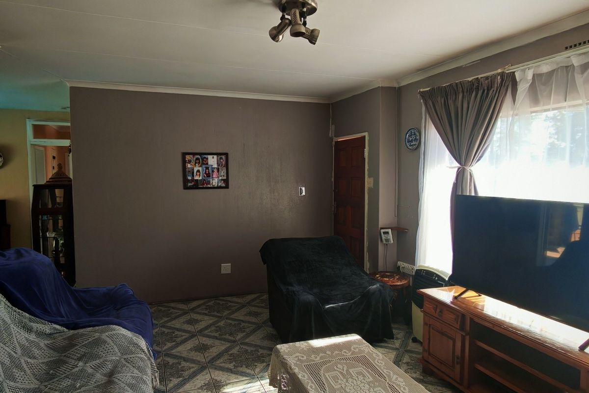 A living room featuring tiled flooring, a large window allowing natural light, and neutral wall tones, providing a functional and comfortable living space.