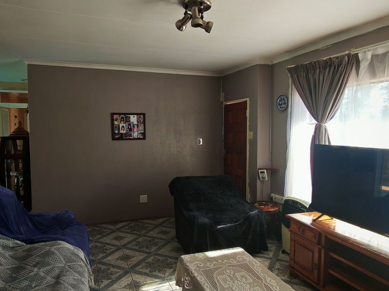 A living room featuring tiled flooring, a large window allowing natural light, and neutral wall tones, providing a functional and comfortable living space.