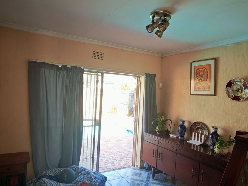 A living room featuring tiled flooring and a sliding door with a security gate, providing direct access to the outdoor area.