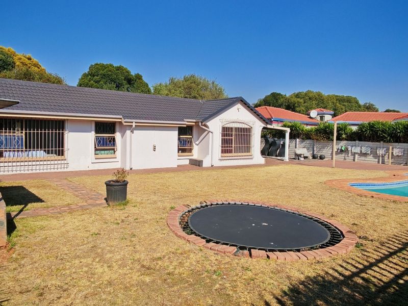 Rear view of the property featuring a swimming pool, paved patio area, and a secure backyard with perimeter walling.