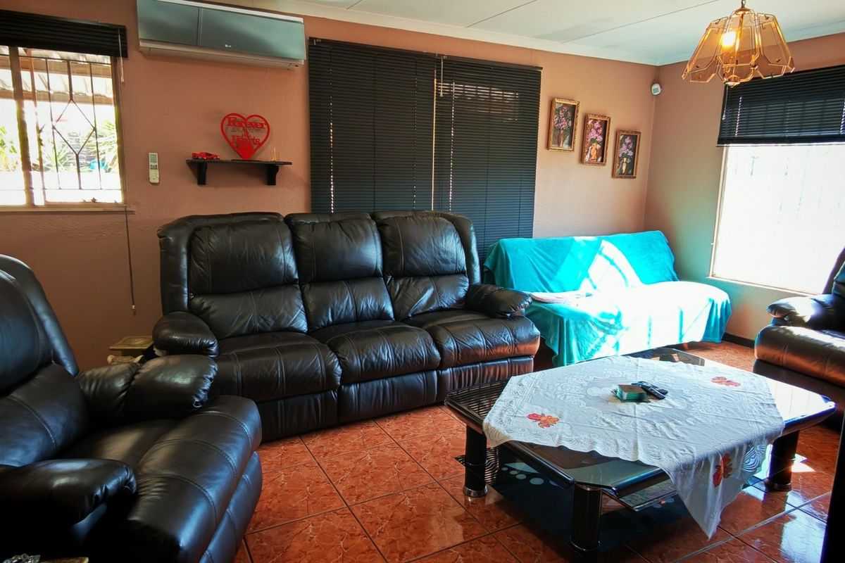 A living room featuring tiled flooring, air conditioning, and security bars on the windows, providing a functional and lived-in space.