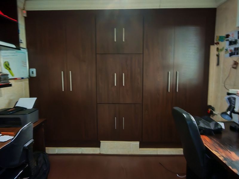 A functional home office featuring extensive built-in dark wood cabinetry and integrated desk space, providing ample storage and workspace.