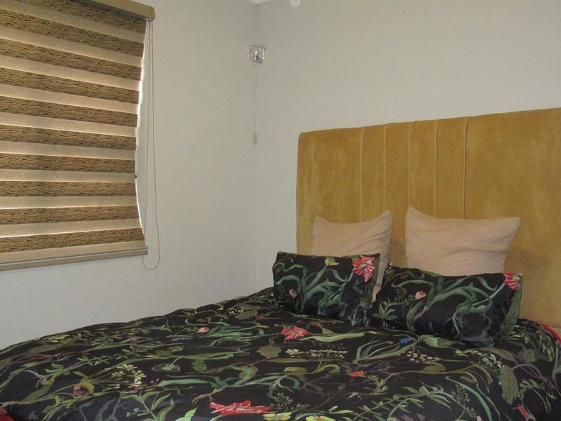 A bedroom featuring a neutral wall finish and a fitted roller blind.