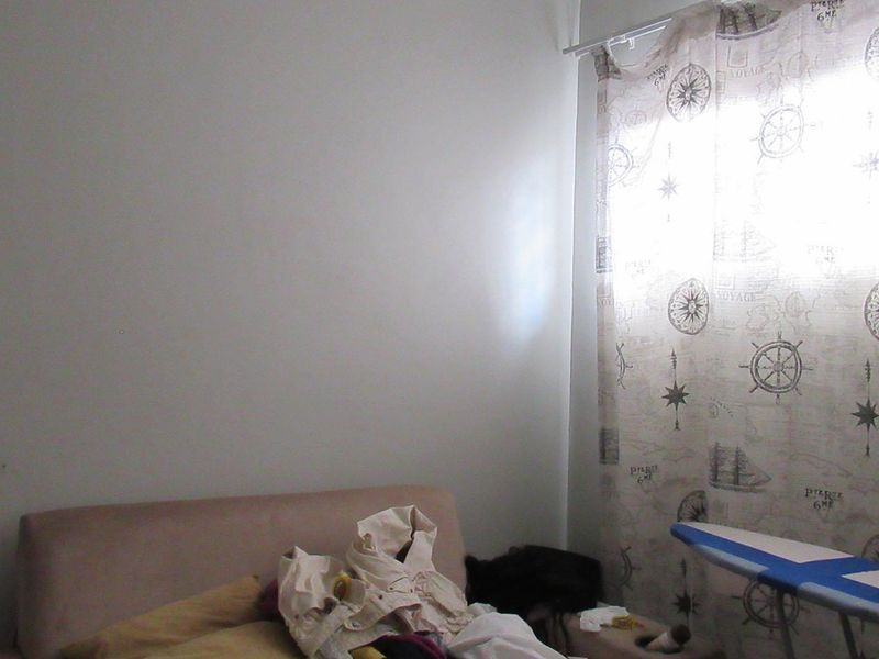 A bedroom space featuring a window with patterned curtains, providing a neutral canvas for potential interior updates and styling.