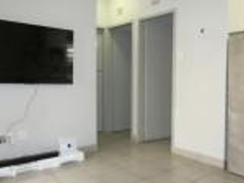 A simple living area featuring tiled flooring and access to adjacent rooms, presented in a neutral, vacant state.
