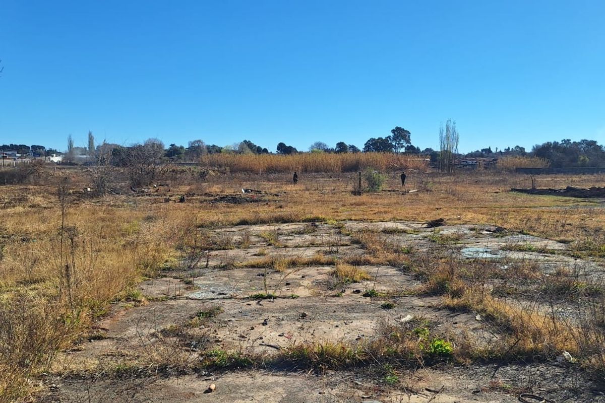 Expansive undeveloped small holding land featuring a weathered concrete slab foundation amidst dry, overgrown vegetation and open field space.