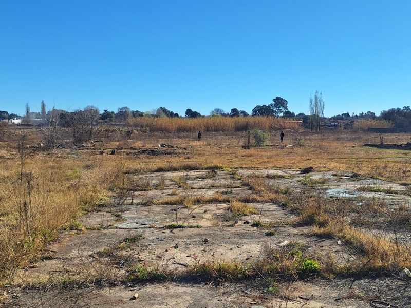 Expansive undeveloped small holding land featuring a weathered concrete slab foundation amidst dry, overgrown vegetation and open field space.